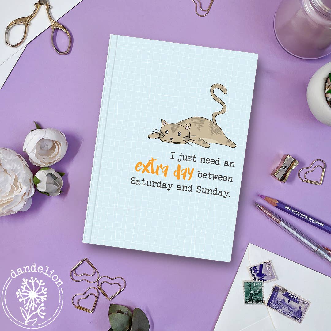 Notebook with a cat illustration and text on a purple surface with stationery items.