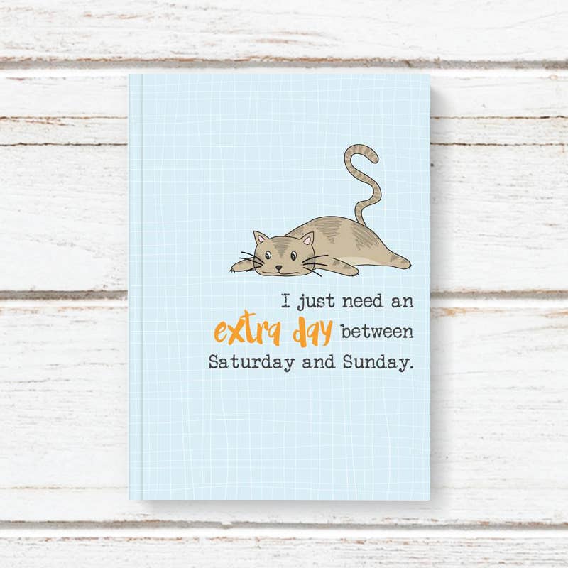Notebook with a cat illustration and text on a wooden surface