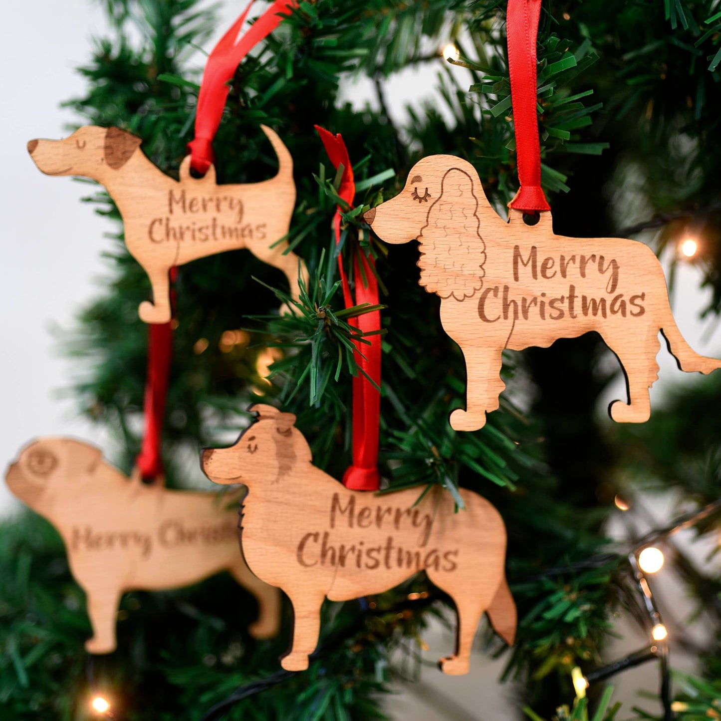 Wooden dog-shaped Christmas ornaments with 'Merry Christmas' text on a decorated tree.