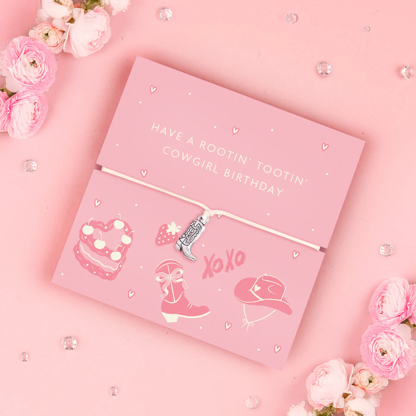 Adjustable bracelet with a cowboy boot charm, displayed on a pink card with cowgirl-themed illustrations and surrounded by flowers.