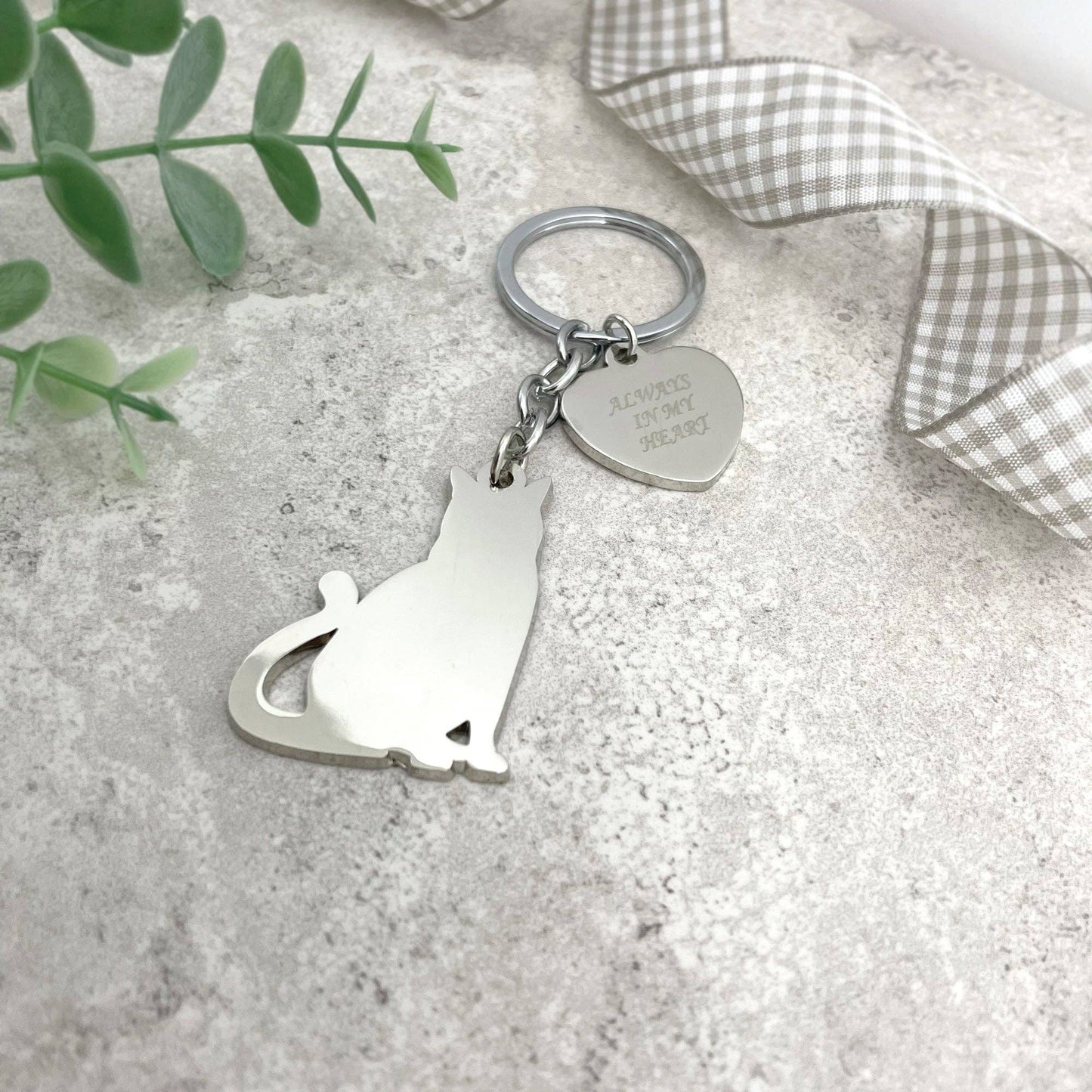 a cat keyring with a heart charm on a stone surface