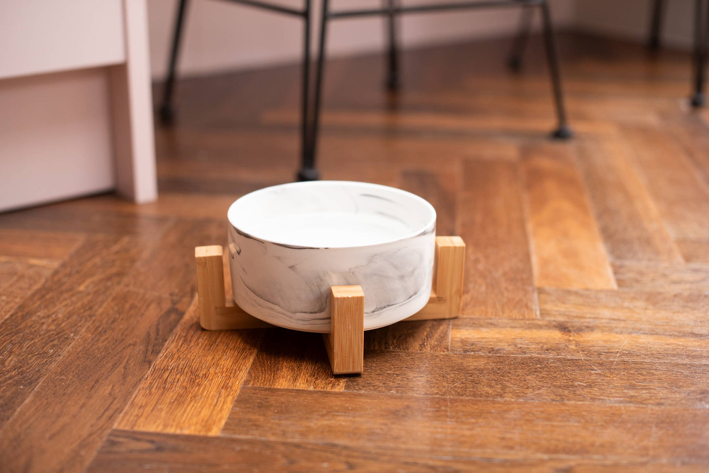 White bowl on a wooden stand on a wooden floor