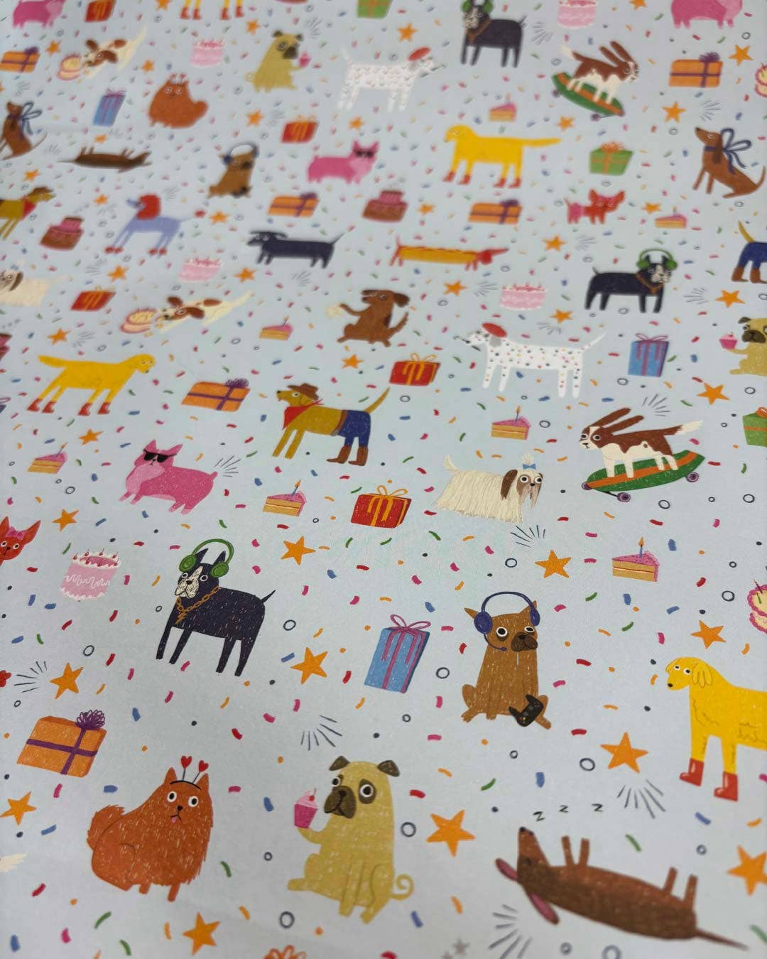 Patterned wrapping paper with colourful dog illustrations on a light blue background