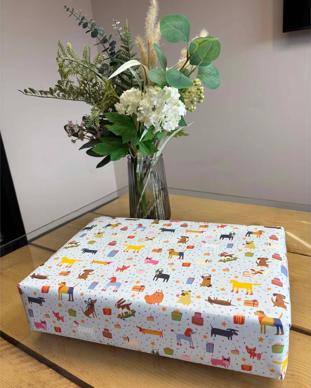 Box with animal pattern on a wooden surface with a vase of flowers in the background