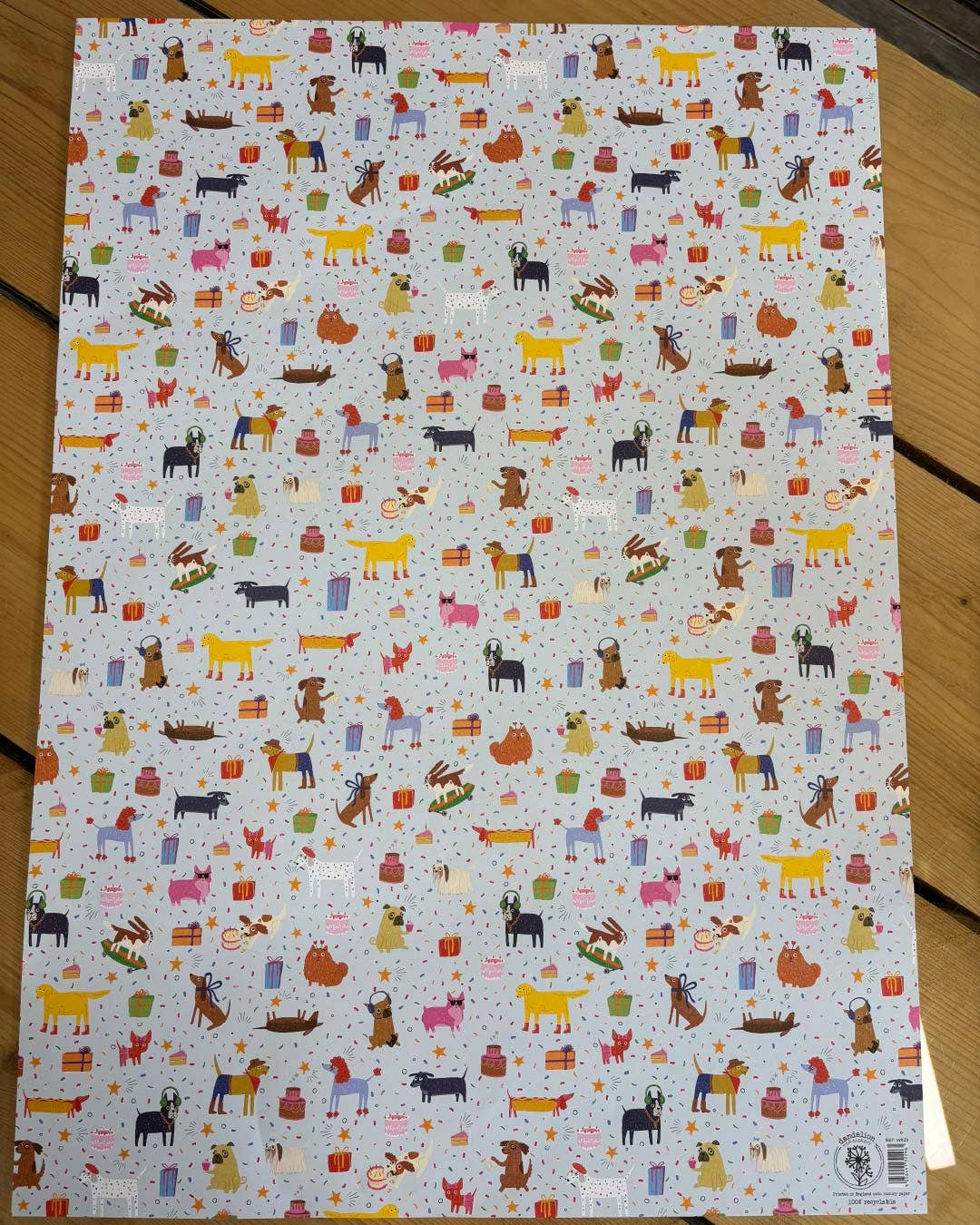 Sheet of paper with colourful dog illustrations on a wooden surface