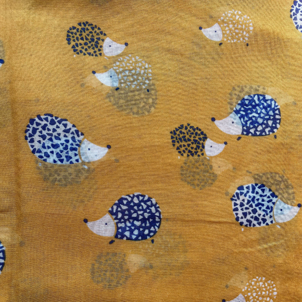 A mustard yellow material with navy blue and white hedgehogs printed on it.