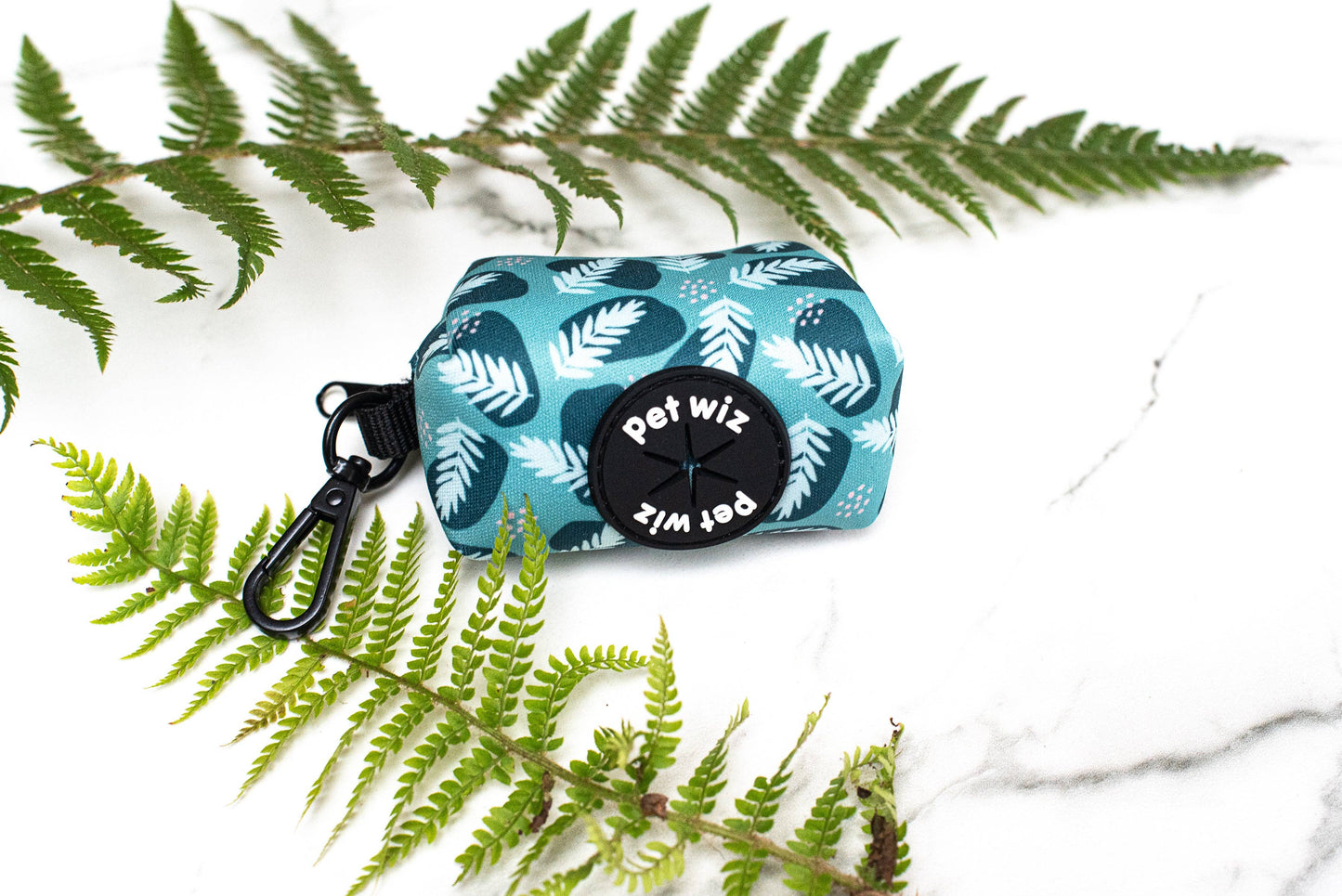 Poo bag holder with white leaf pattern and 'Pet wiz' branding on a white background with green fern leaves.