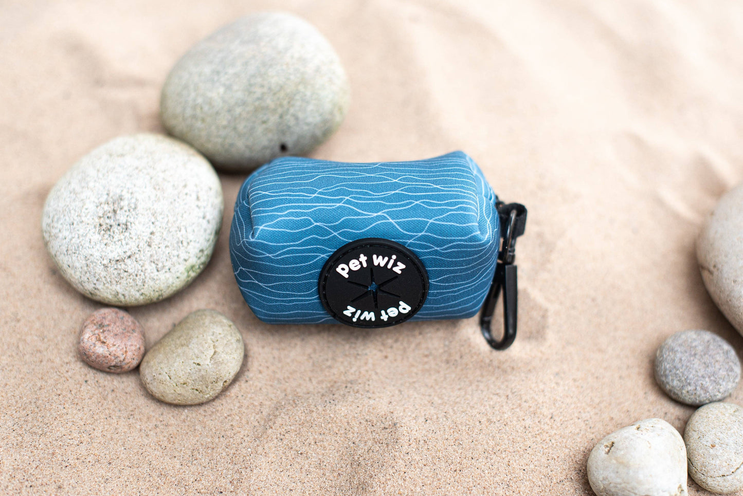 Poo bag holder with 'Pet Wiz' branding on a sandy background with stones