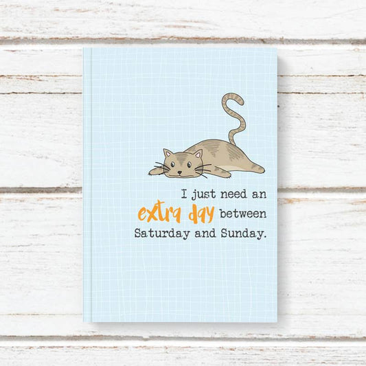 Notebook with a cat illustration and text on a wooden surface