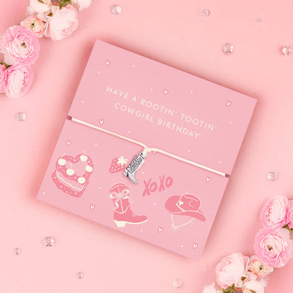 Adjustable bracelet with a cowboy boot charm, displayed on a pink card with cowgirl-themed illustrations and surrounded by flowers.