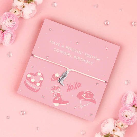 Adjustable bracelet with a cowboy boot charm, displayed on a pink card with cowgirl-themed illustrations and surrounded by flowers.