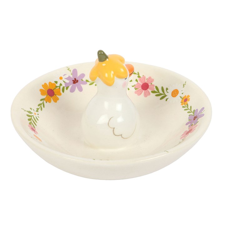 Decorative ring holder with floral patterns and a small figurine on a white background