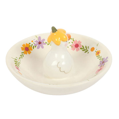 Decorative ring holder with floral patterns and a small figurine on a white background