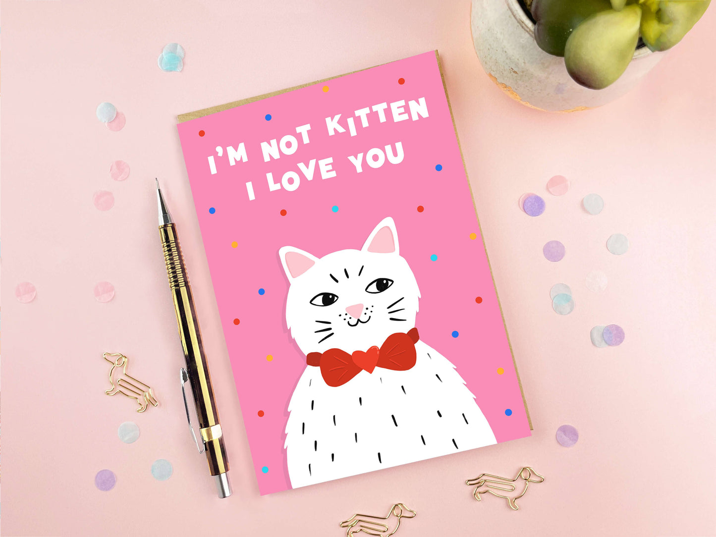 Card with a cat illustration and text 'I'm not kitten, I love you' on a pink background with confetti.