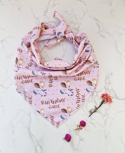 Pink dog bandana with 'Birthday Girl' text on a marble surface