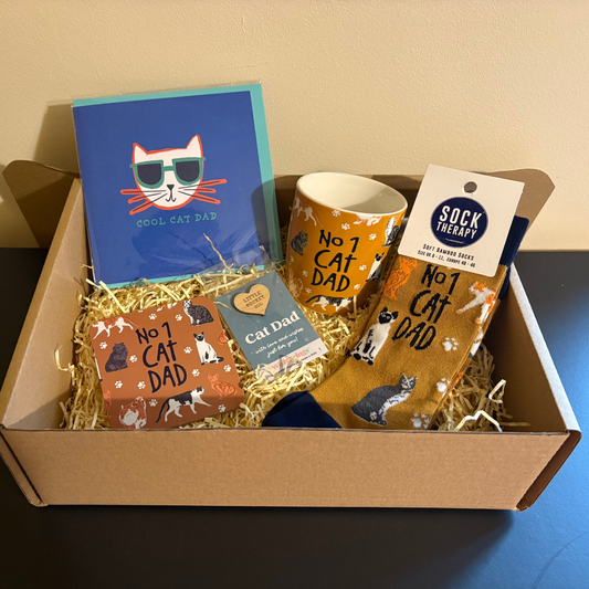 Gift set for a cat dad with mug, socks, cards, and book in a box.