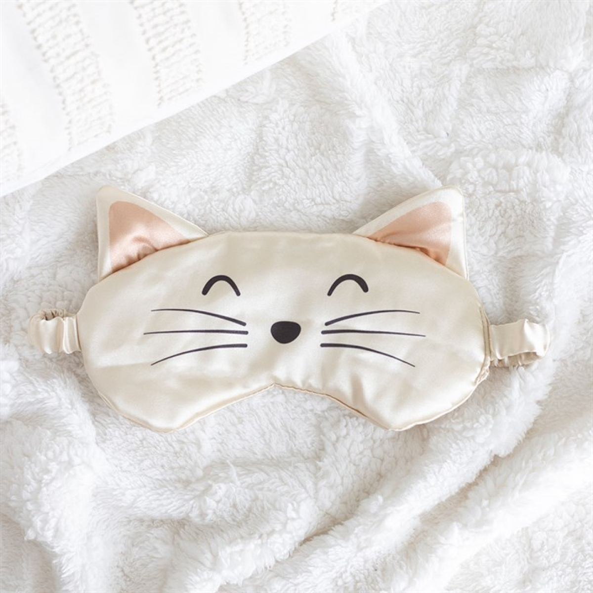 Cat-shaped sleep mask on a soft white background