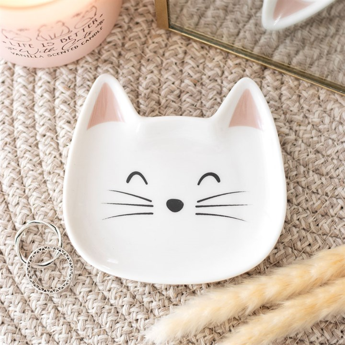 Cat-shaped ceramic dish on a textured surface with decorative elements.