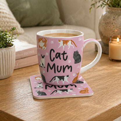 Pink mug with cat illustrations and 'Cat Mum' text on a coaster, placed on a wooden surface.