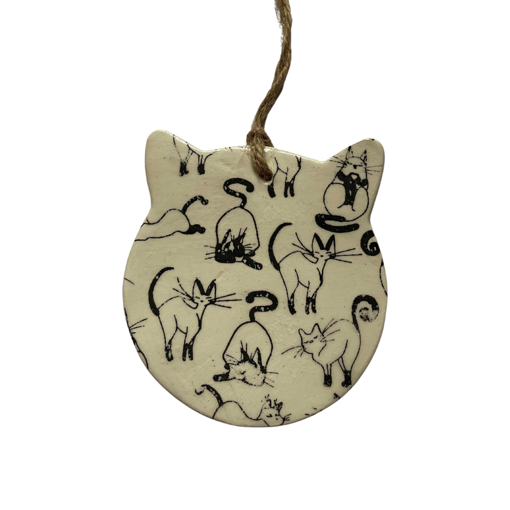 Decorative hanging ceramic with cat illustrations on a beige background