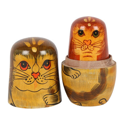Two wooden nesting dolls with cat designs on a white background