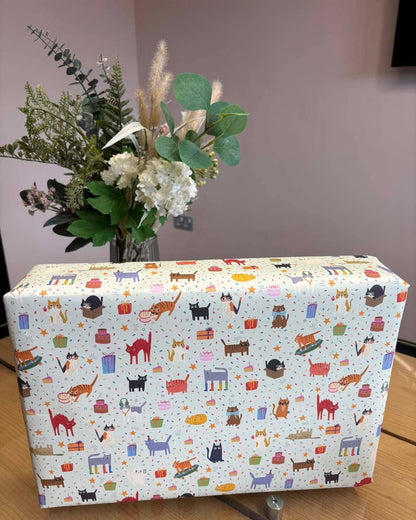 Box with a colourful cat pattern on a wooden surface with flowers in the background