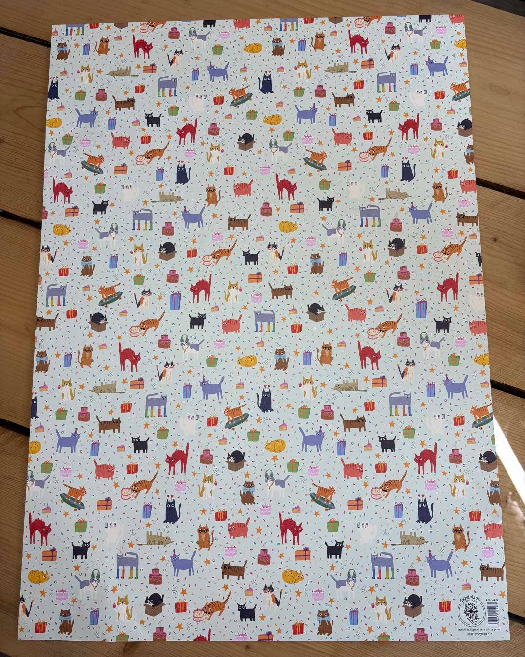 Sheet of paper with colourful cat pattern on a wooden surface