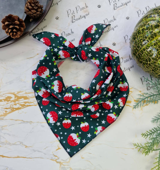 Christmas-themed dog bandana with red berries and green leaves on a marble surface.