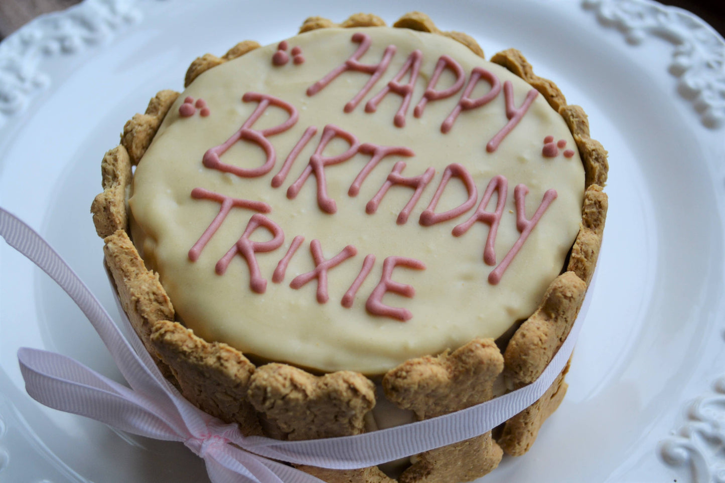 Dog birthday cake with 'Happy Birthday Trixie' on a white plate
