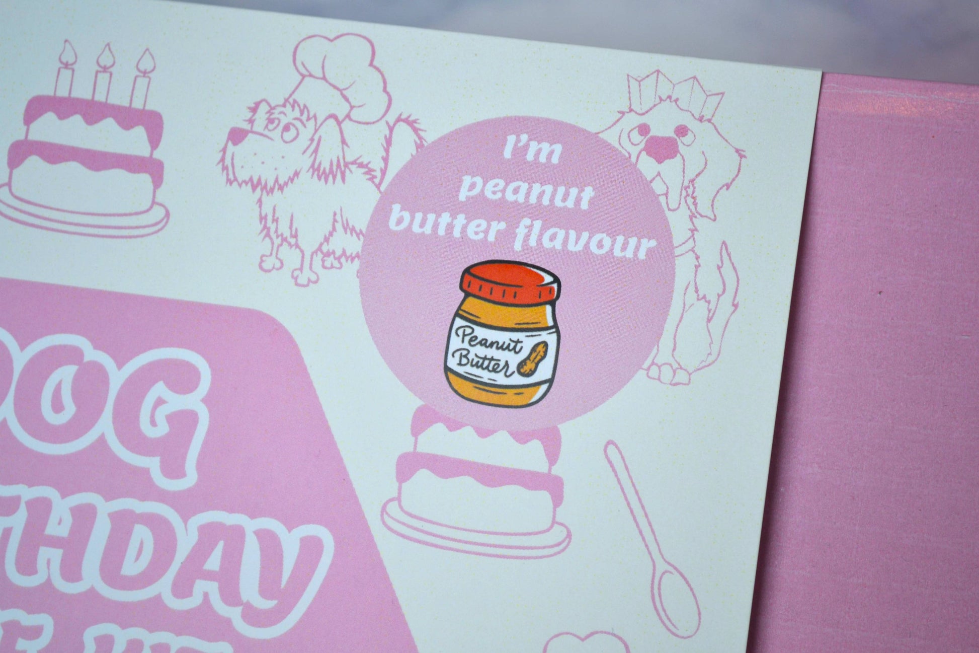 Dog birthday card with illustrations of a dog, cake, and peanut butter jar on a pink background.
