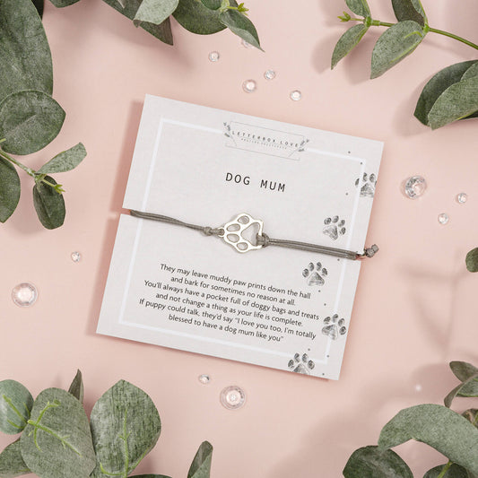 Adjustable bracelet with a dog paw print charm and a poem card, presented on a pink background with green leaves.