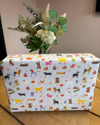 Box with dog patterned paper and a vase of flowers on a wooden surface