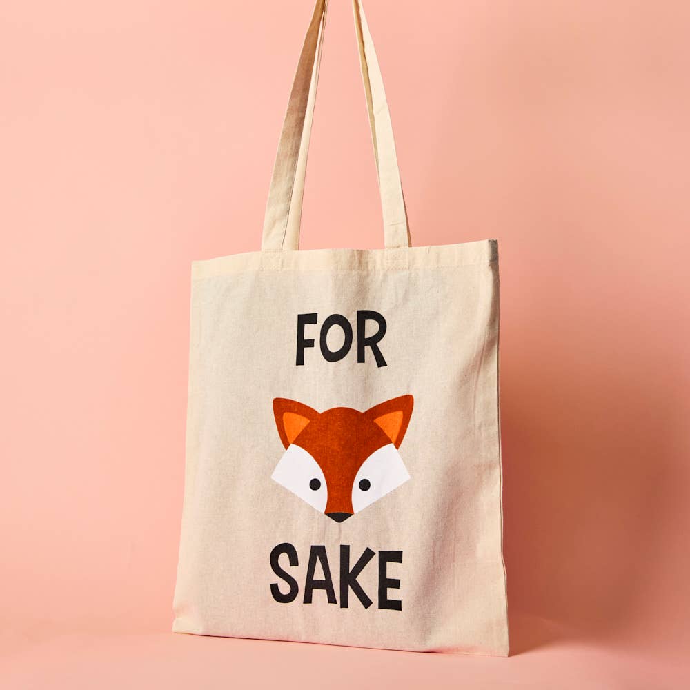 A beige cotton tote bag with the text 'FOR FOX SAKE' printed on the front, featuring a cartoon illustration of a fox's face.