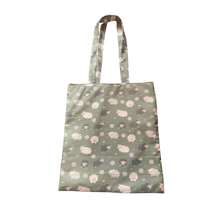 Green tote bag with sheep pattern on a white background