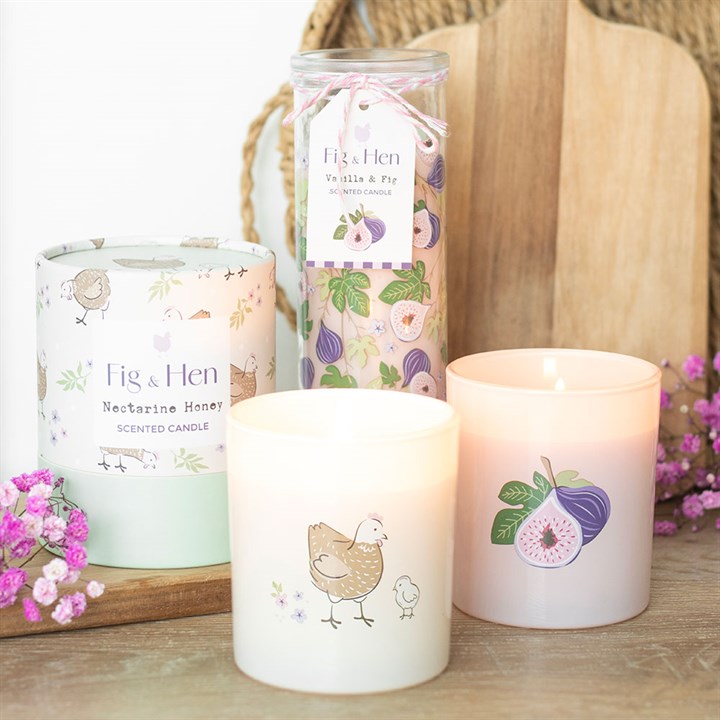 Fig & Hen candles with floral design packaging on a wooden surface.