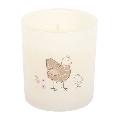 Candle with a design of a mother hen and chick on a white background