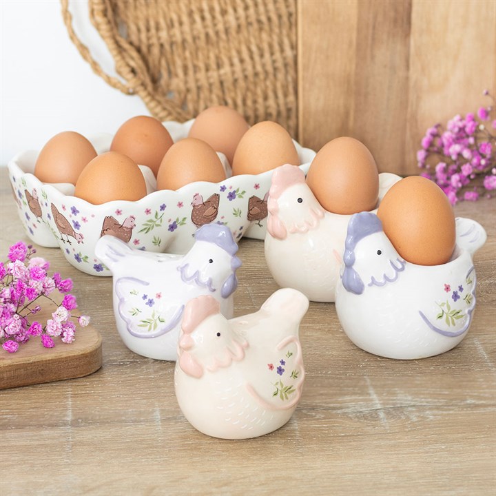 Decorative ceramic chicken egg holders with eggs on a wooden surface.