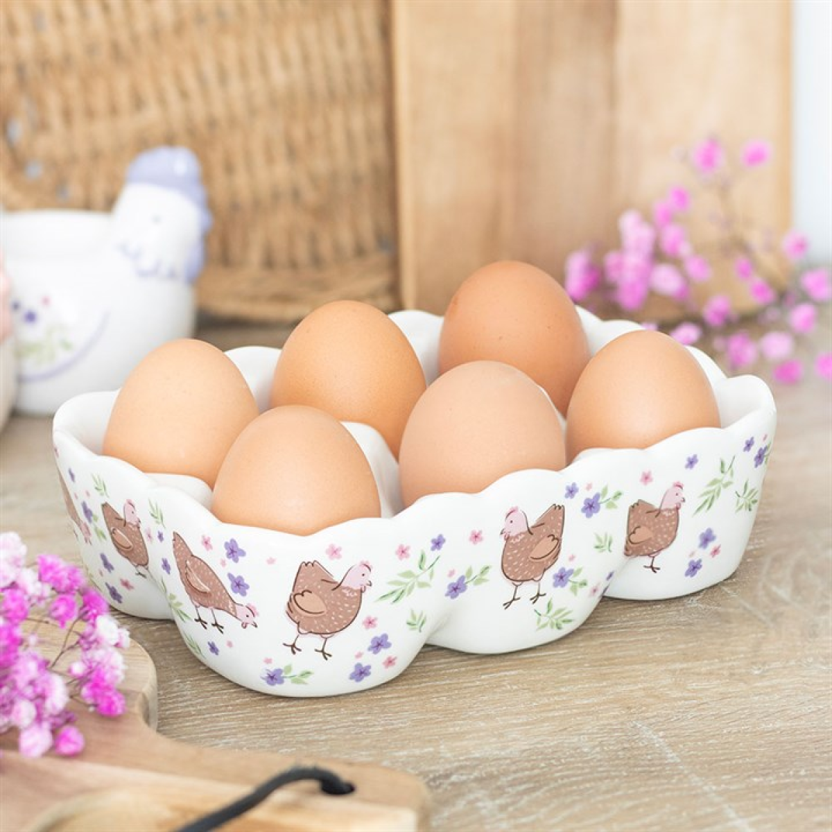 Decorative ceramic egg tray with eggs on a wooden surface with flowers.