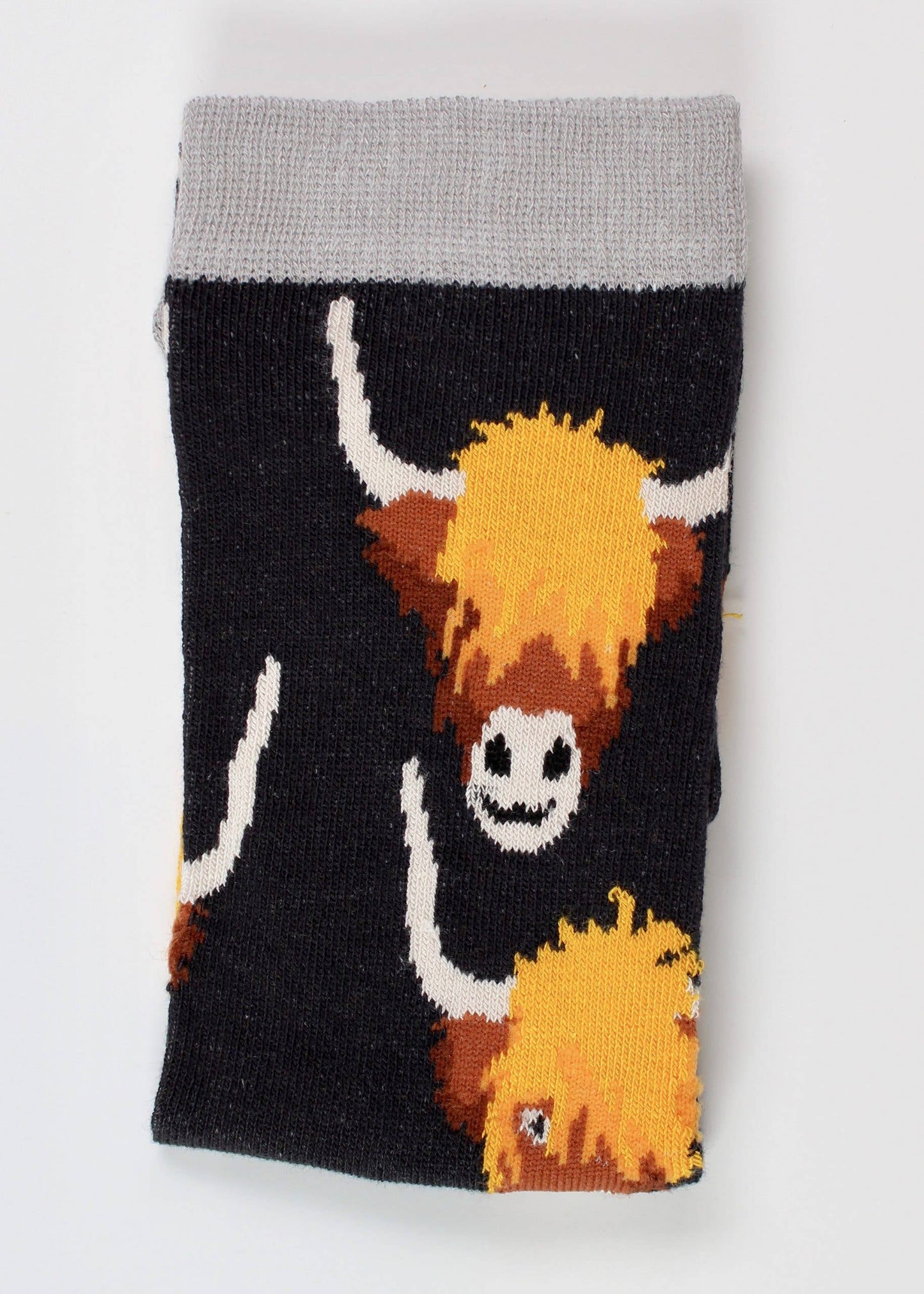 Highland cow design on a black pair of socks with grey trim.