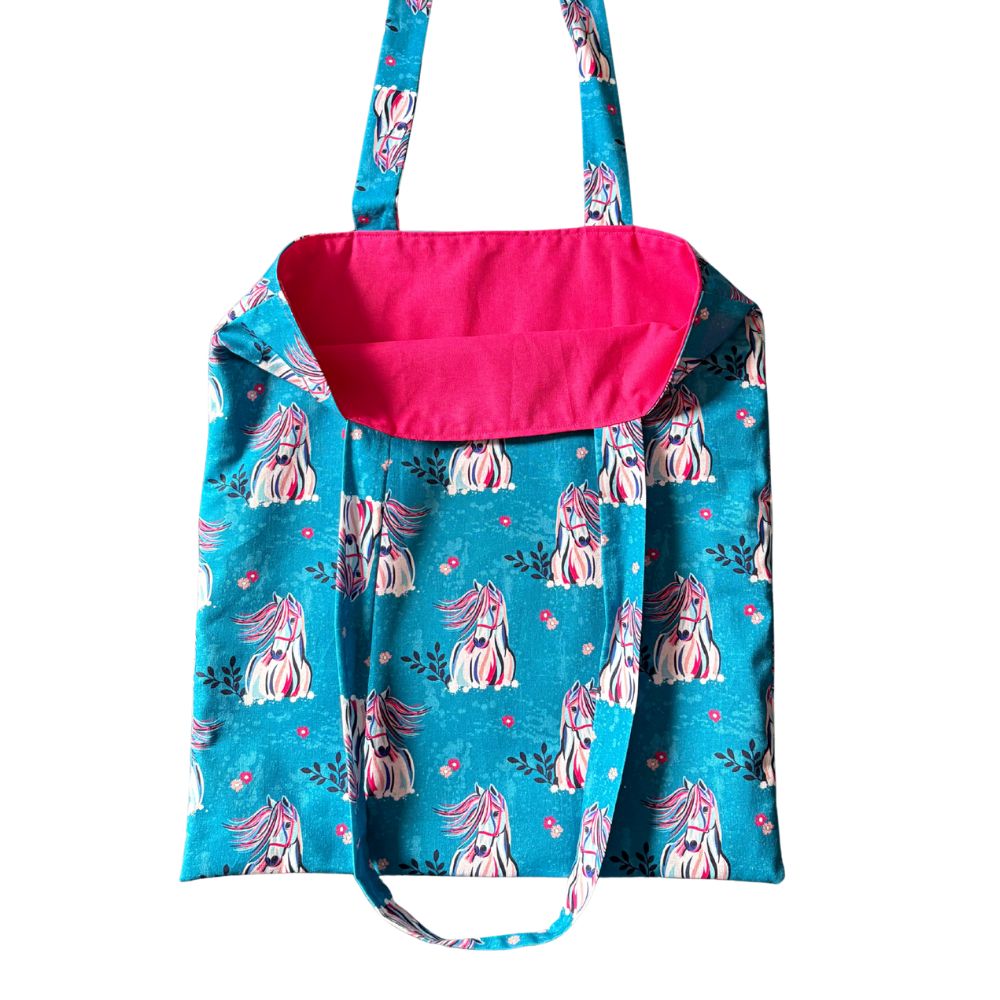 Blue bag with pink interior and horse pattern on a white background