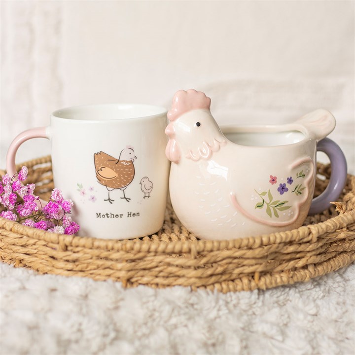 Ceramic mug with 'Mother Hen' design and chicken-shaped creamer on a woven tray.