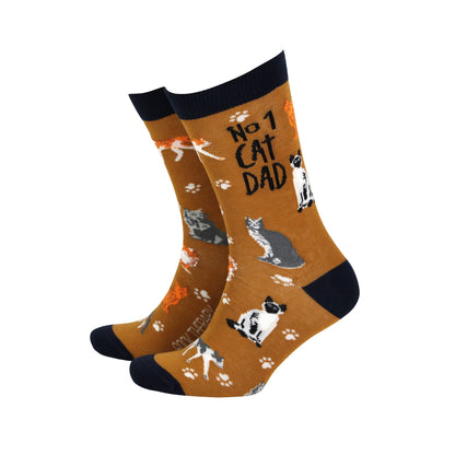A pair of brown bamboo socks with text 'No.1 CAT DAD' and various cat illustrations.