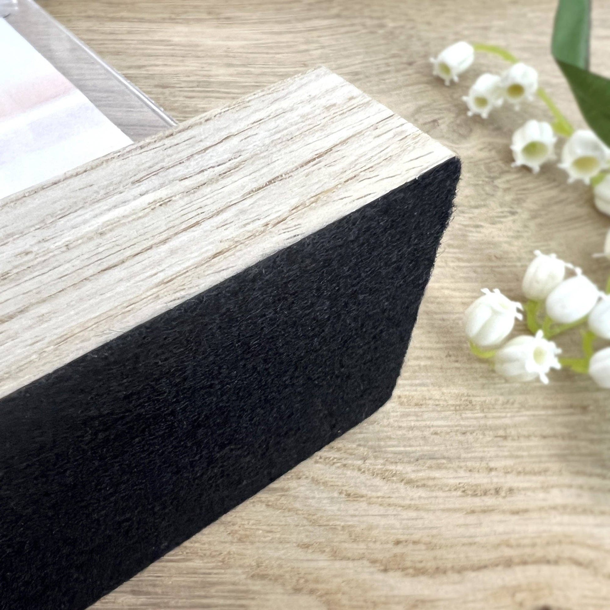 Black foam pad on a wooden surface with white flowers in the background