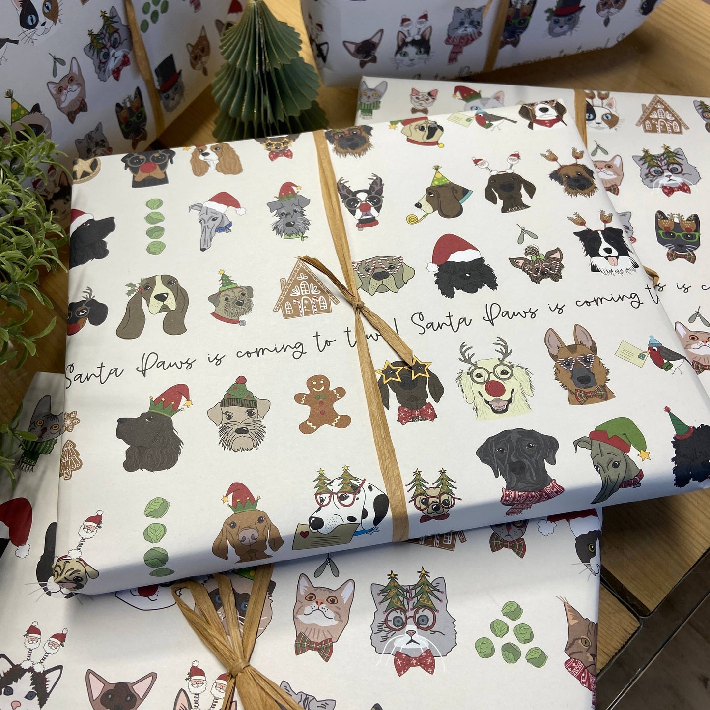 Gift wrap with festive dog designs and text on a wooden surface.