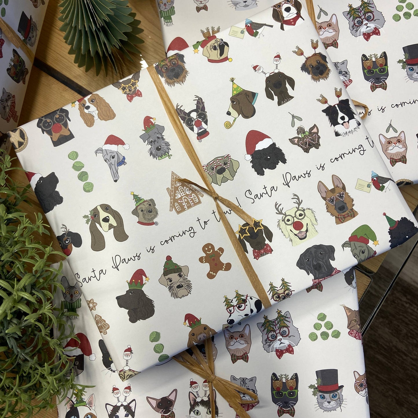 Christmas-themed wrapping paper with dog illustrations on a wooden surface.