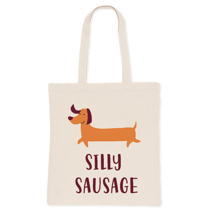 A white cotton tote bag with an illustration of a cartoon dog and the phrase 'SILLY SAUSAGE' printed on the front.