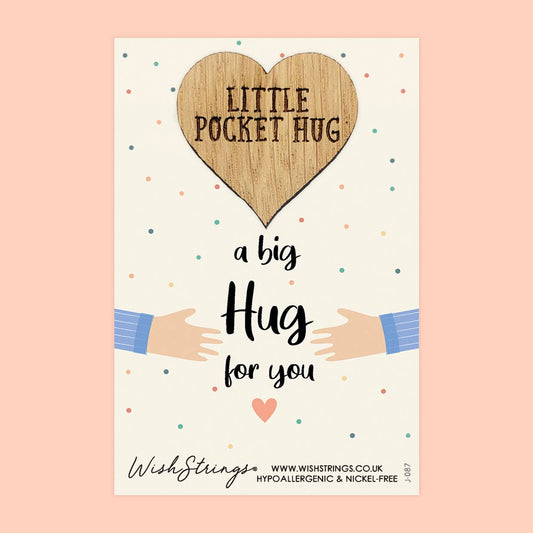 Heart-shaped wooden tag with 'Little Pocket Hug' text, surrounded by cartoon hands and colorful dots on a light pink background.